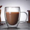 Double-wall glass mug with espresso showing amber swirl and steam, heat-resistant and transparent design