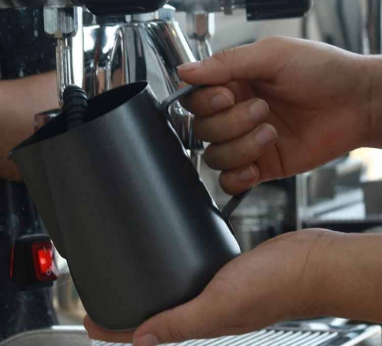 Black stainless steel milk frothing jug with ergonomic handle for home espresso machines